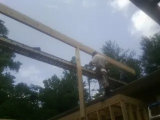 Carpenter setting a ridge beam over a new addition frame — Ice Dam Removal by Roofing Brothers in Atalissa
