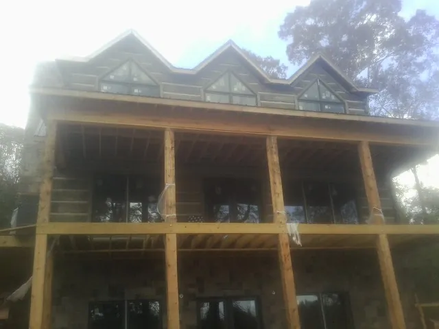 Dormers and porch framing on a large log home under construction — Roof Coating work by our crew in Atalissa