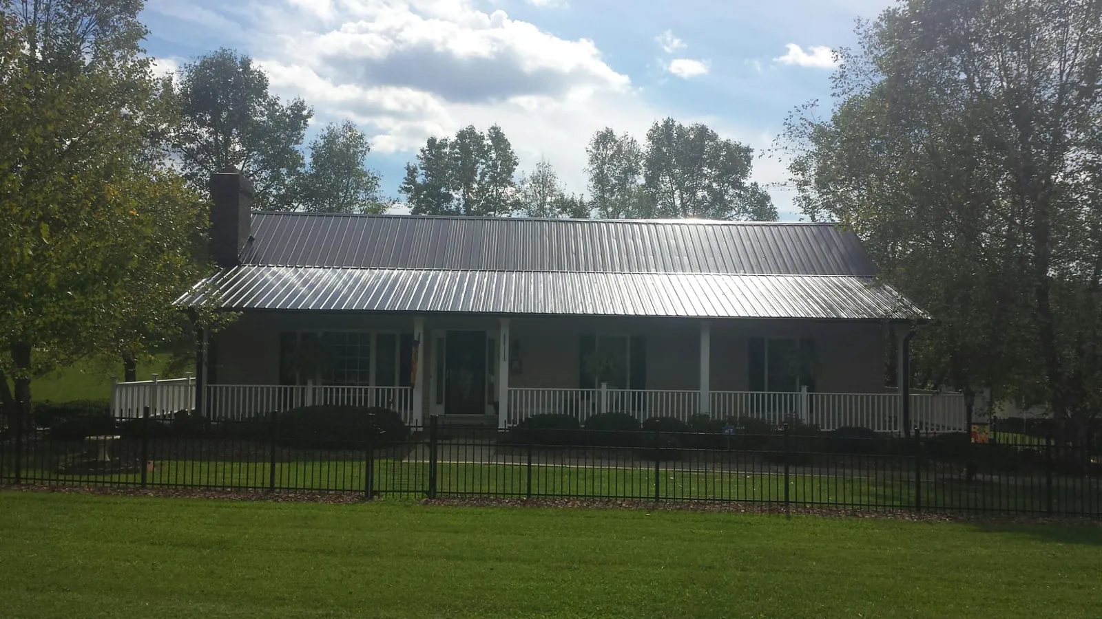 Gray metal roof on a brick ranch with a full width front porch — Gutter Guard Installation work by our crew in Atalissa