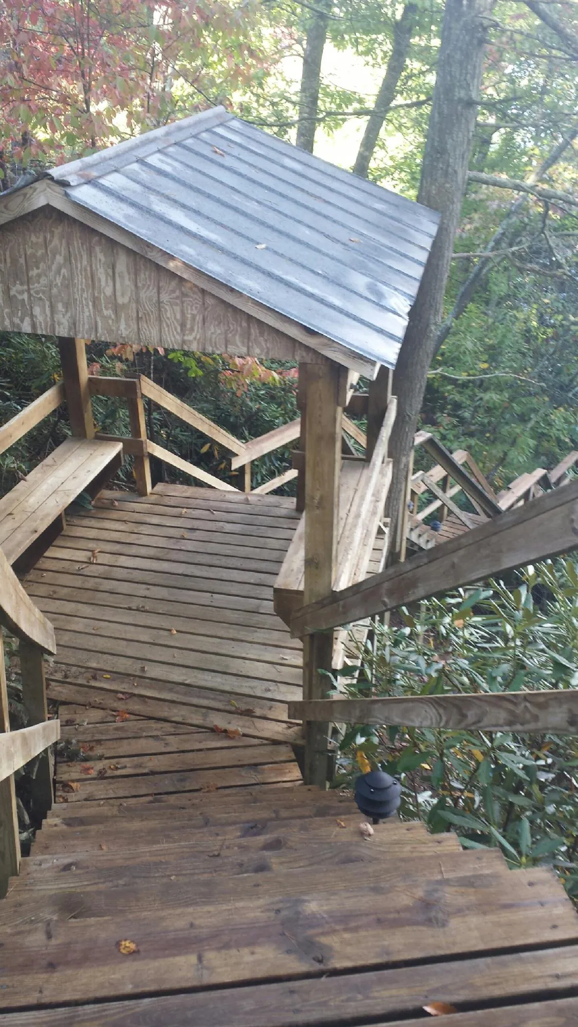 Metal roofed shelter over wooden steps on a wooded walkway — Skylight Repair & Installation work by our crew in Atalissa