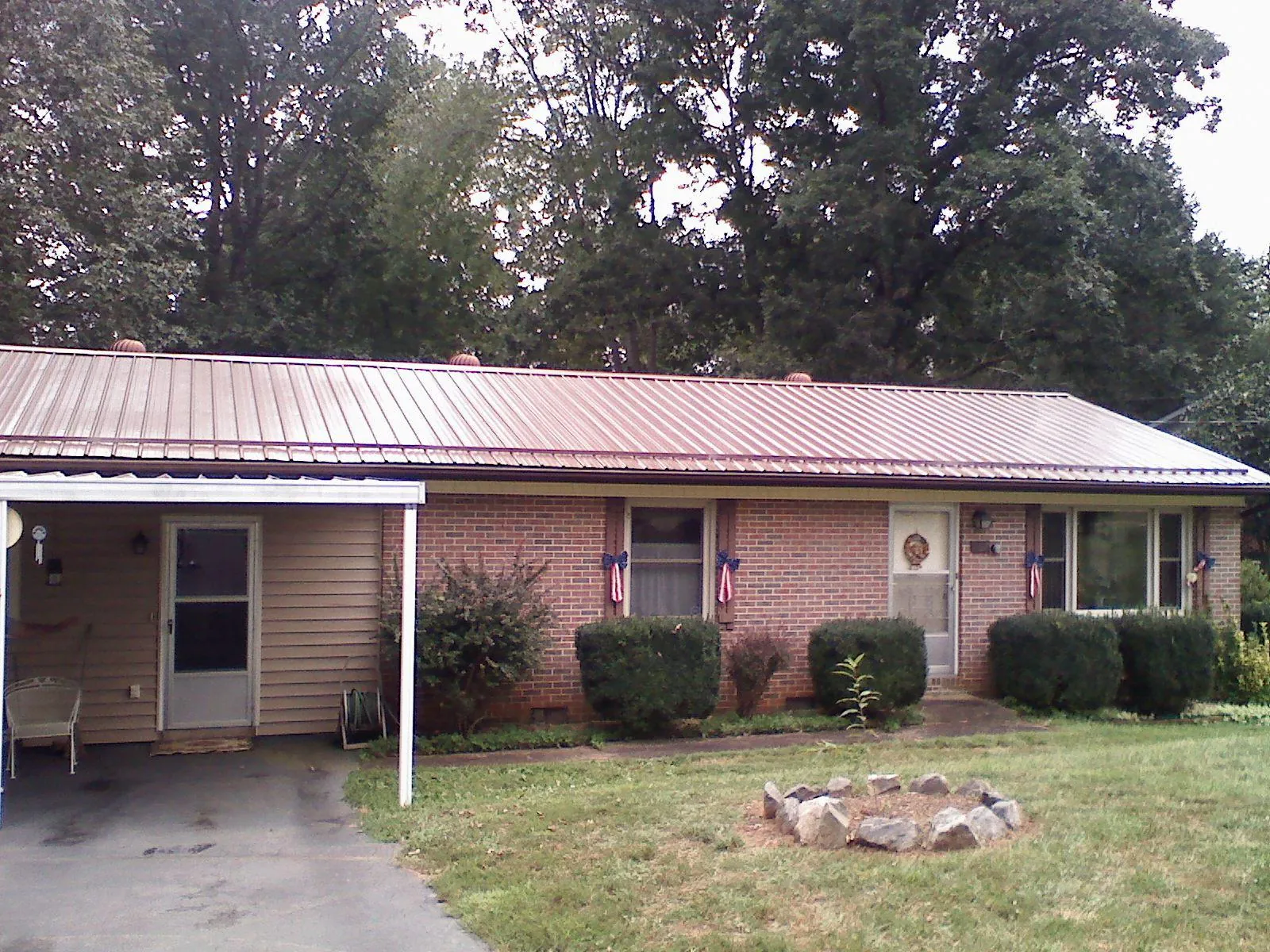 Bronze metal roof and carport on a brick ranch home — Roof Repair work by our crew in Atalissa