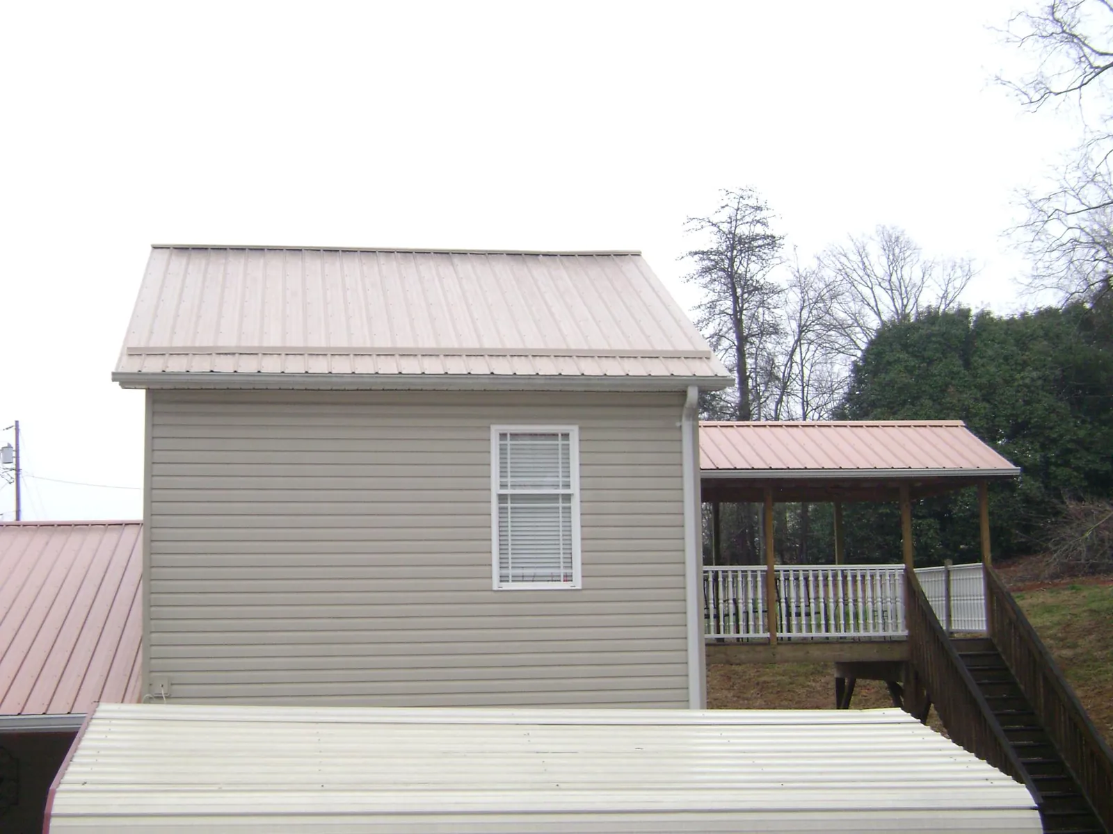 Tan metal roofs on a two story addition and attached porch, from a Roof Replacement job in Atalissa