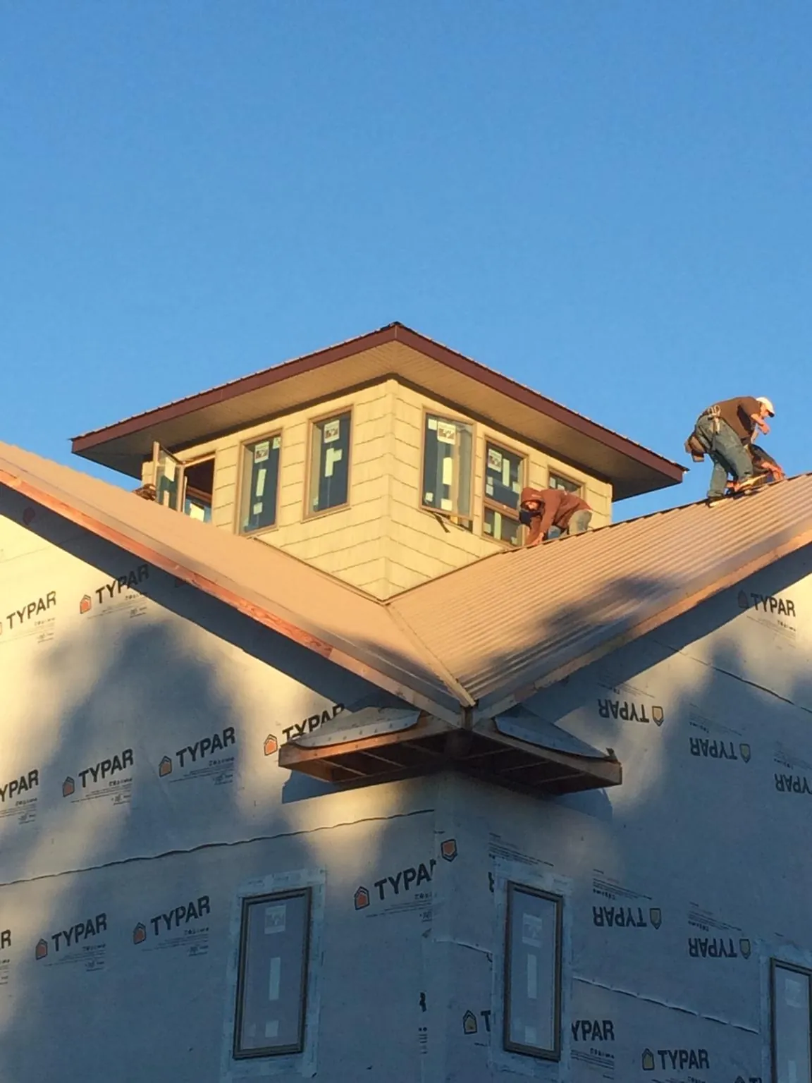 Roofers working around a rooftop cupola on a new metal roof at sunset — Roof Waterproofing in Atalissa by Roofing Brothers